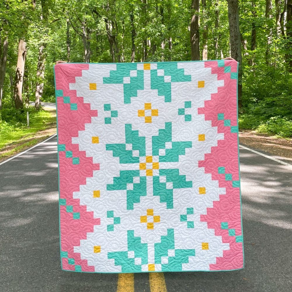 Colorful quilt displayed on forest road.