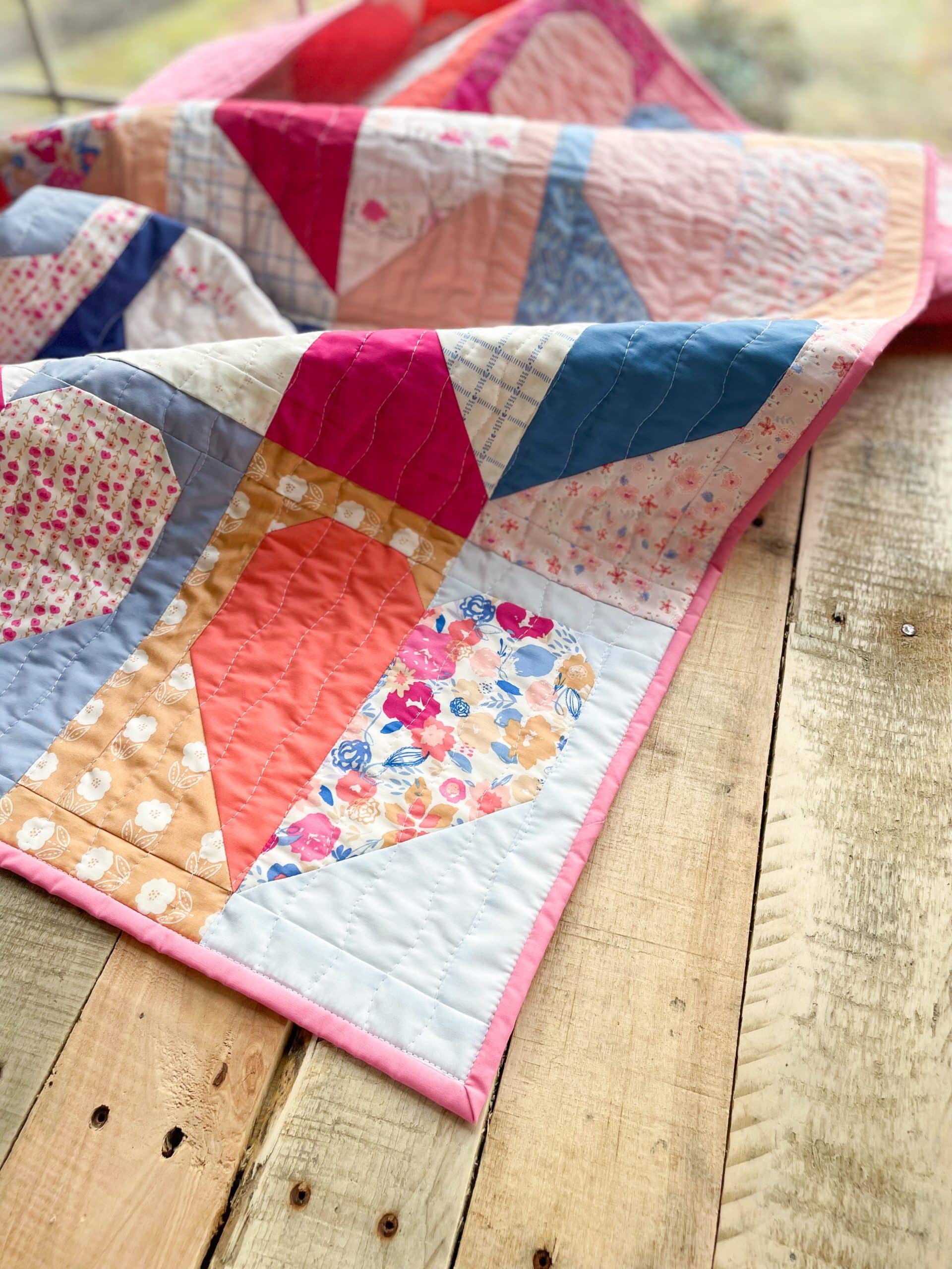 Colorful quilt with floral patterns on wooden table.