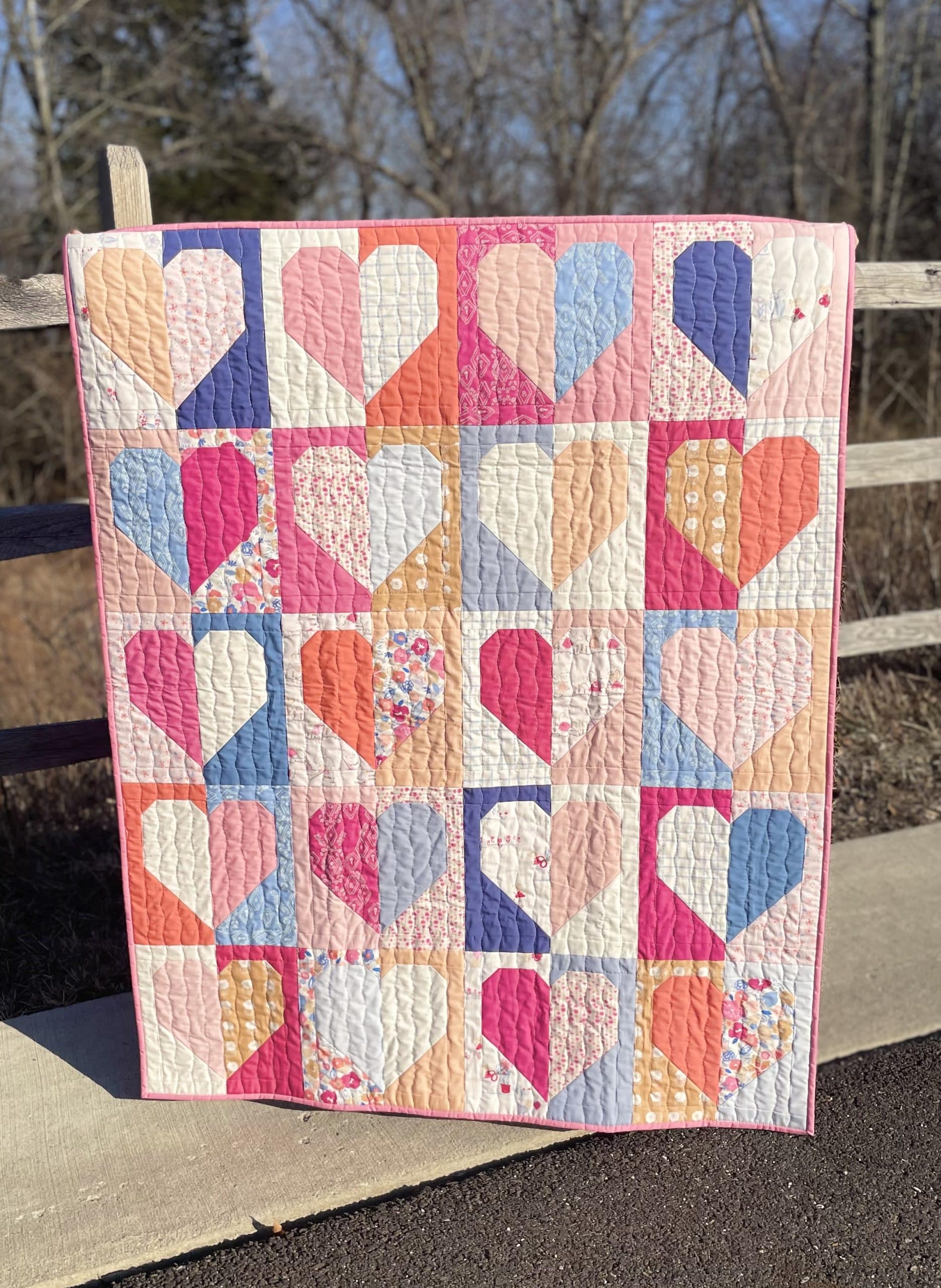 Colorful heart patchwork quilt on wooden fence.