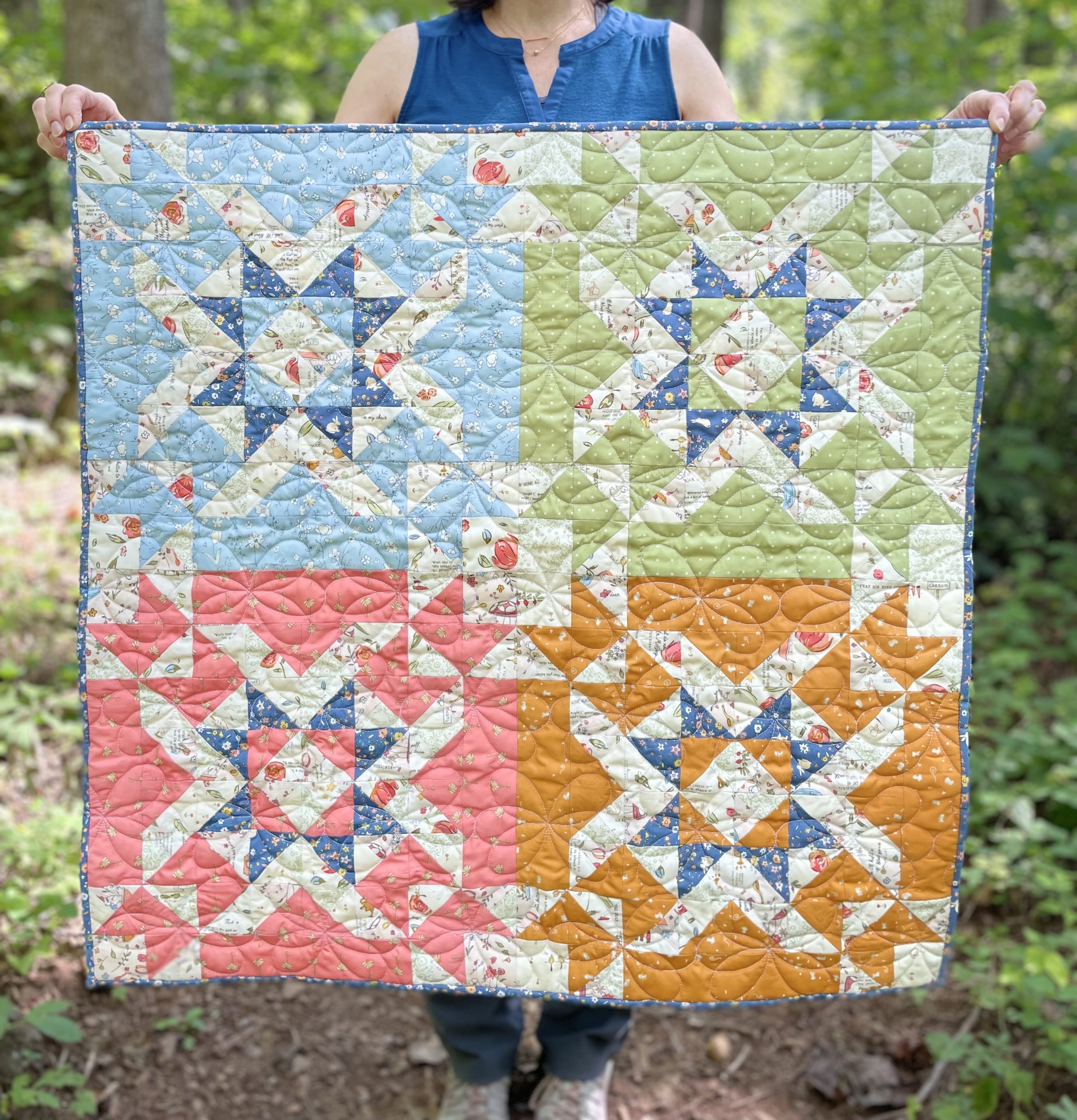 Colorful star pattern quilt held in a forest