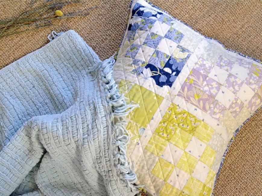 Blue knitted blanket and patchwork quilt pillow