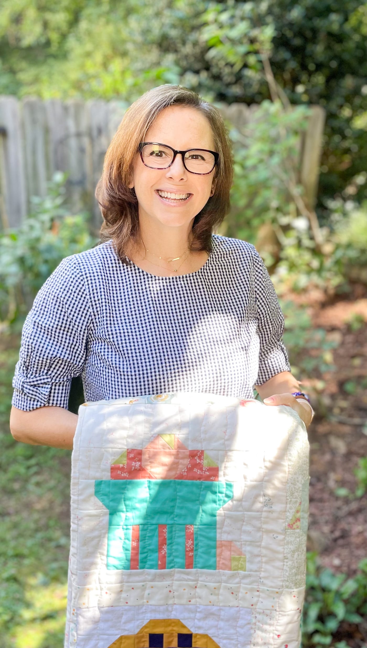 Woman holding colorful handmade quilt outdoors