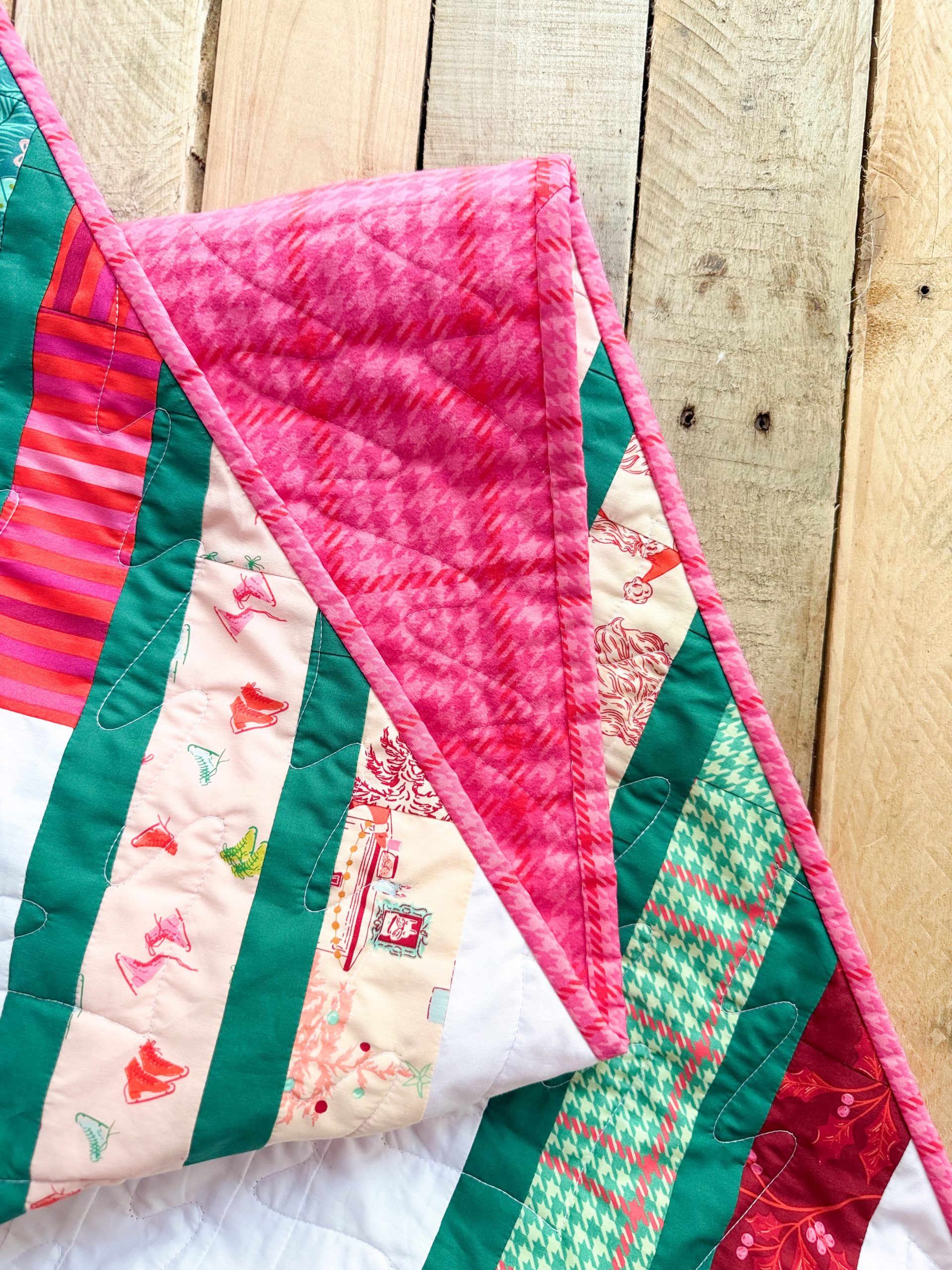 Colorful quilt with pink trim on wooden background