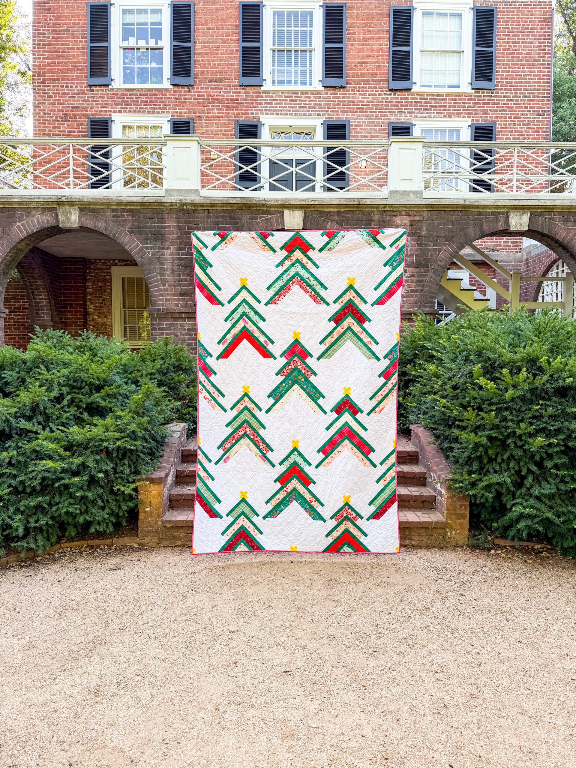 Colorful chevron quilt hanging before brick building