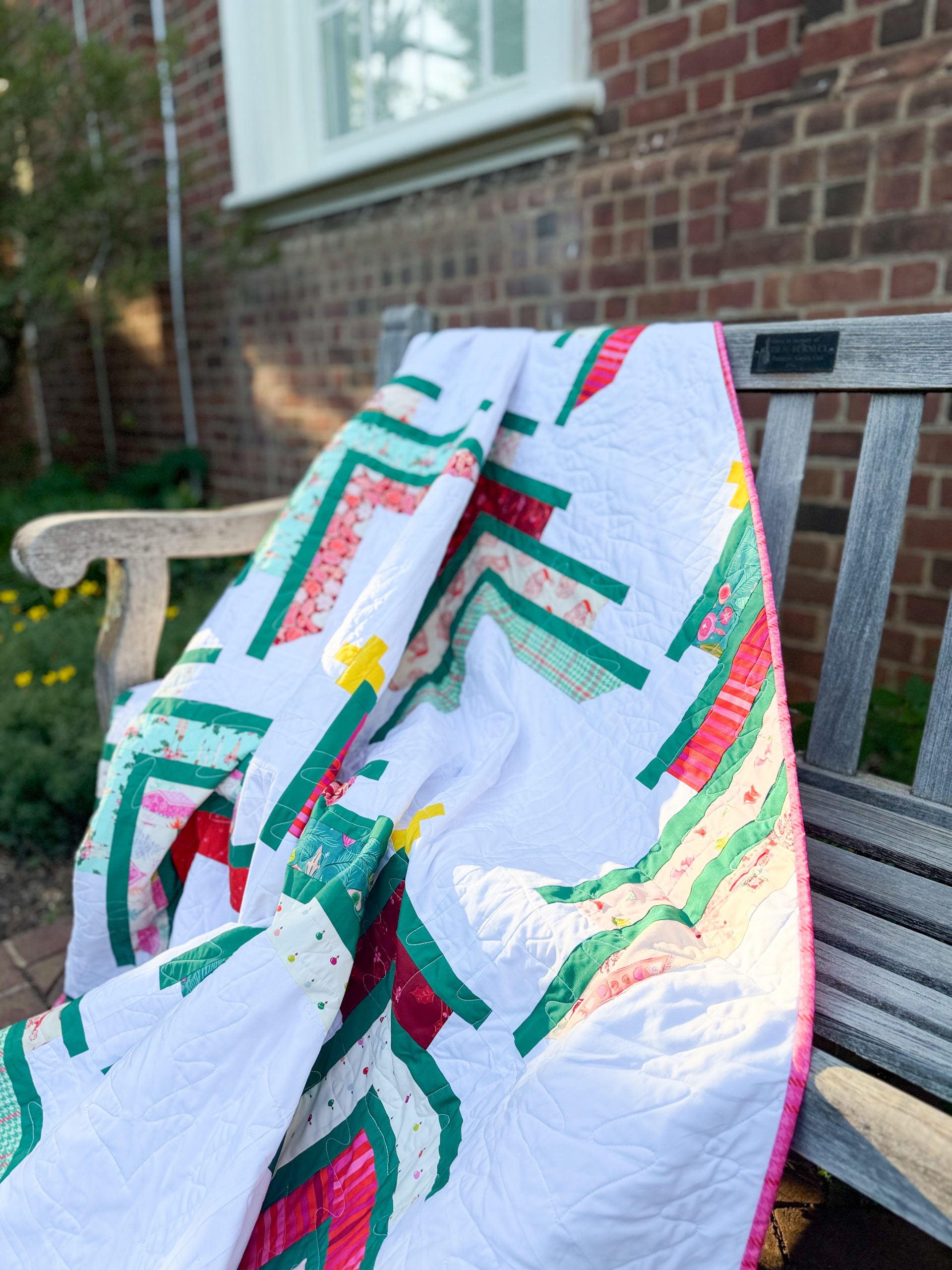 Colorful patchwork quilt draped over wooden bench outdoors