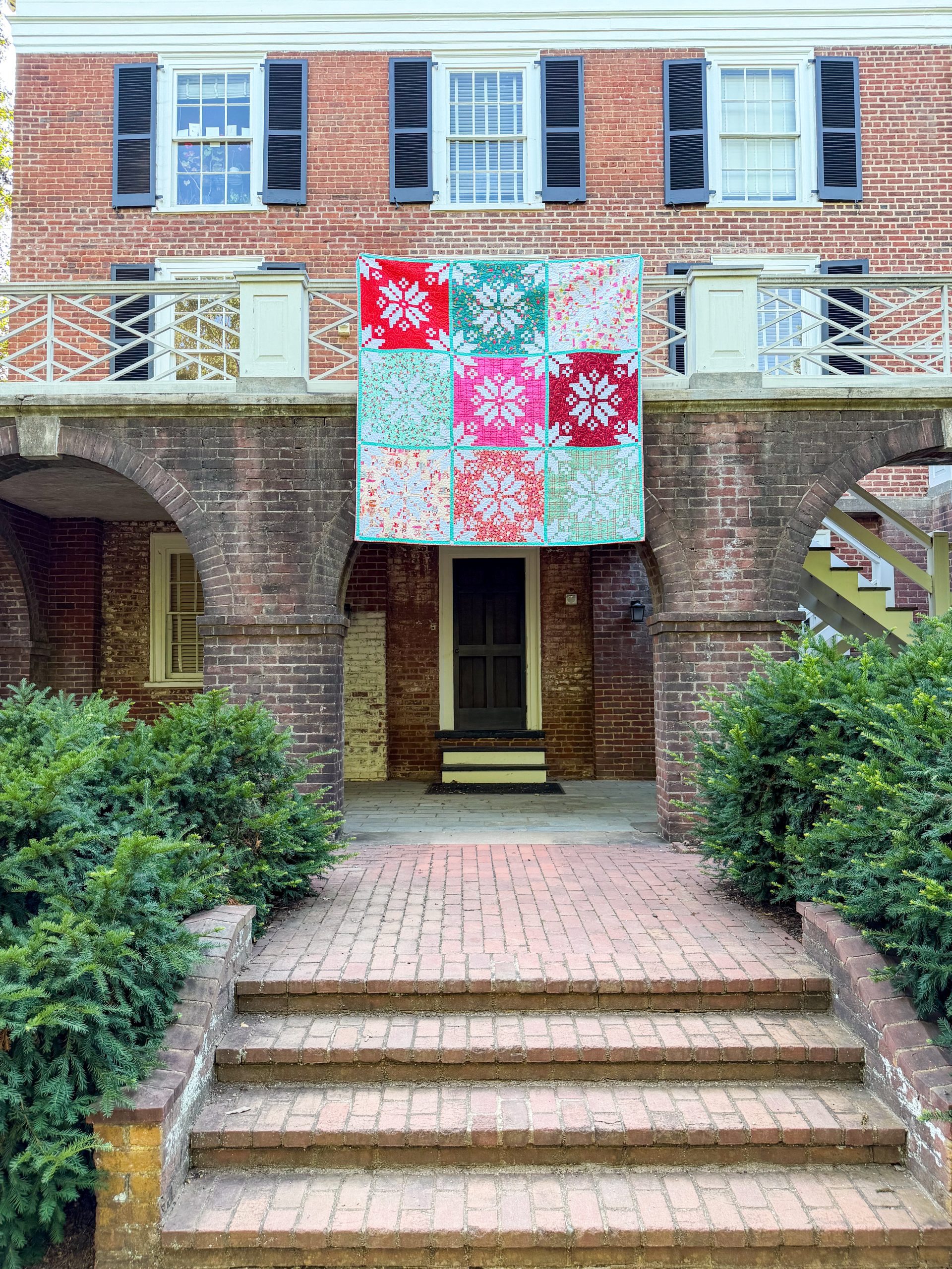 Colorful quilt hanging on brick colonial balcony
