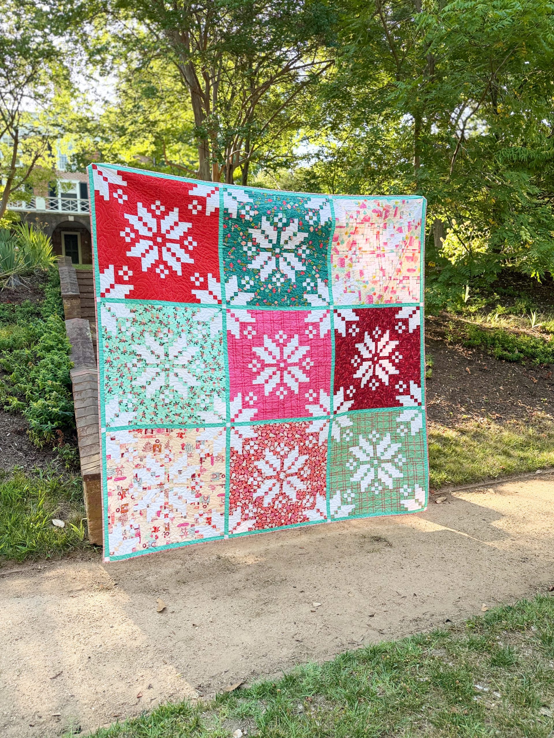 Colorful snowflake patchwork quilt displayed outdoors
